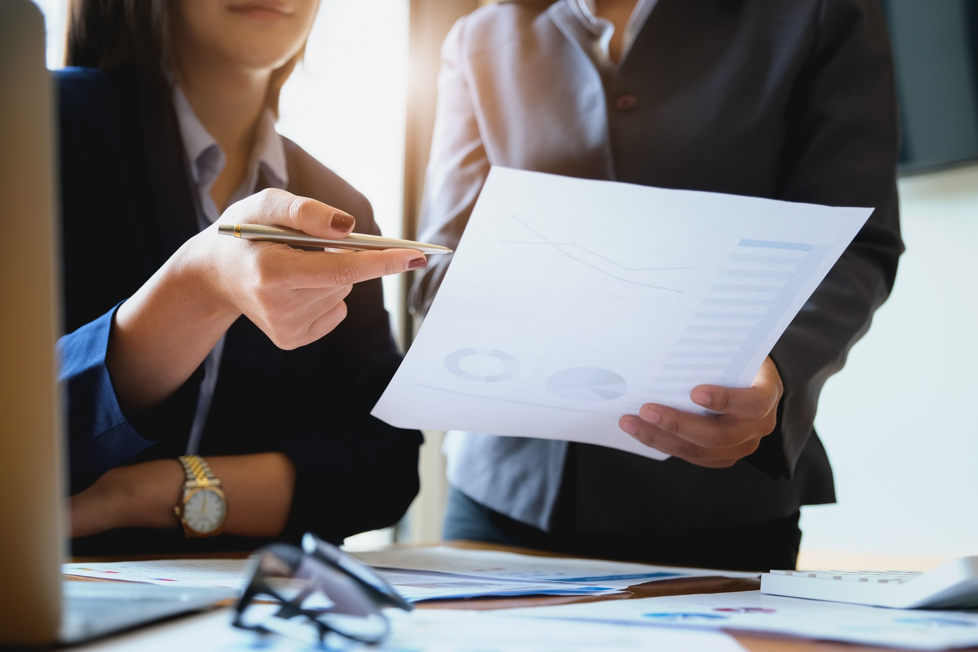 An auditor holds a pen pointing to documents to examine budgets and financial fraud